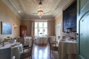 Runde gedeckte Tische im kleinen Gourmet-Restaurant dekoriert mit Gemälden an den Wänden und Stuckdecken im 5 Sterne Tagungshotel Niedersachsen