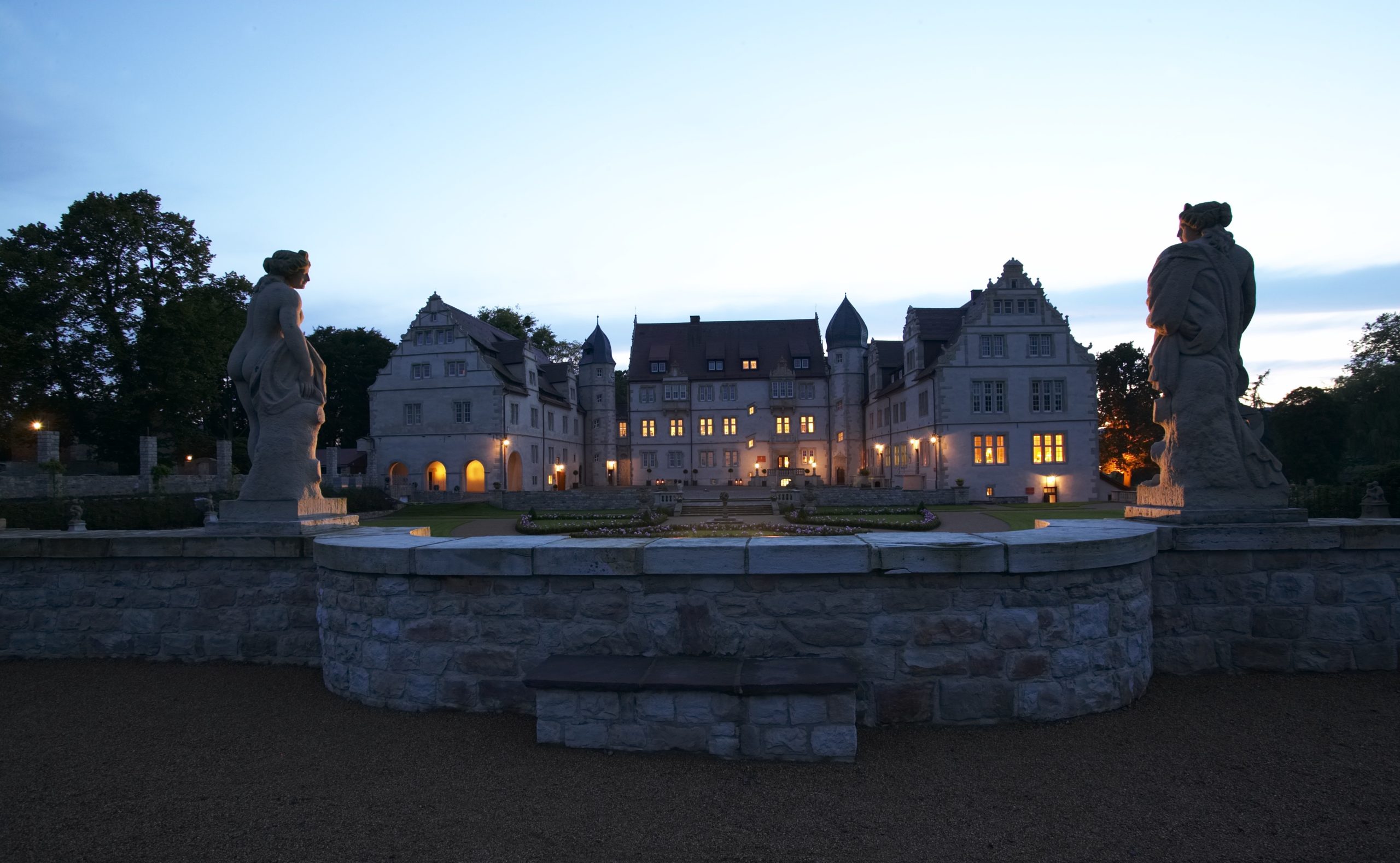 warm illuminiertes Schlosshotel Münchhausen mit davorliegendem gepflegtem Schlossgarten