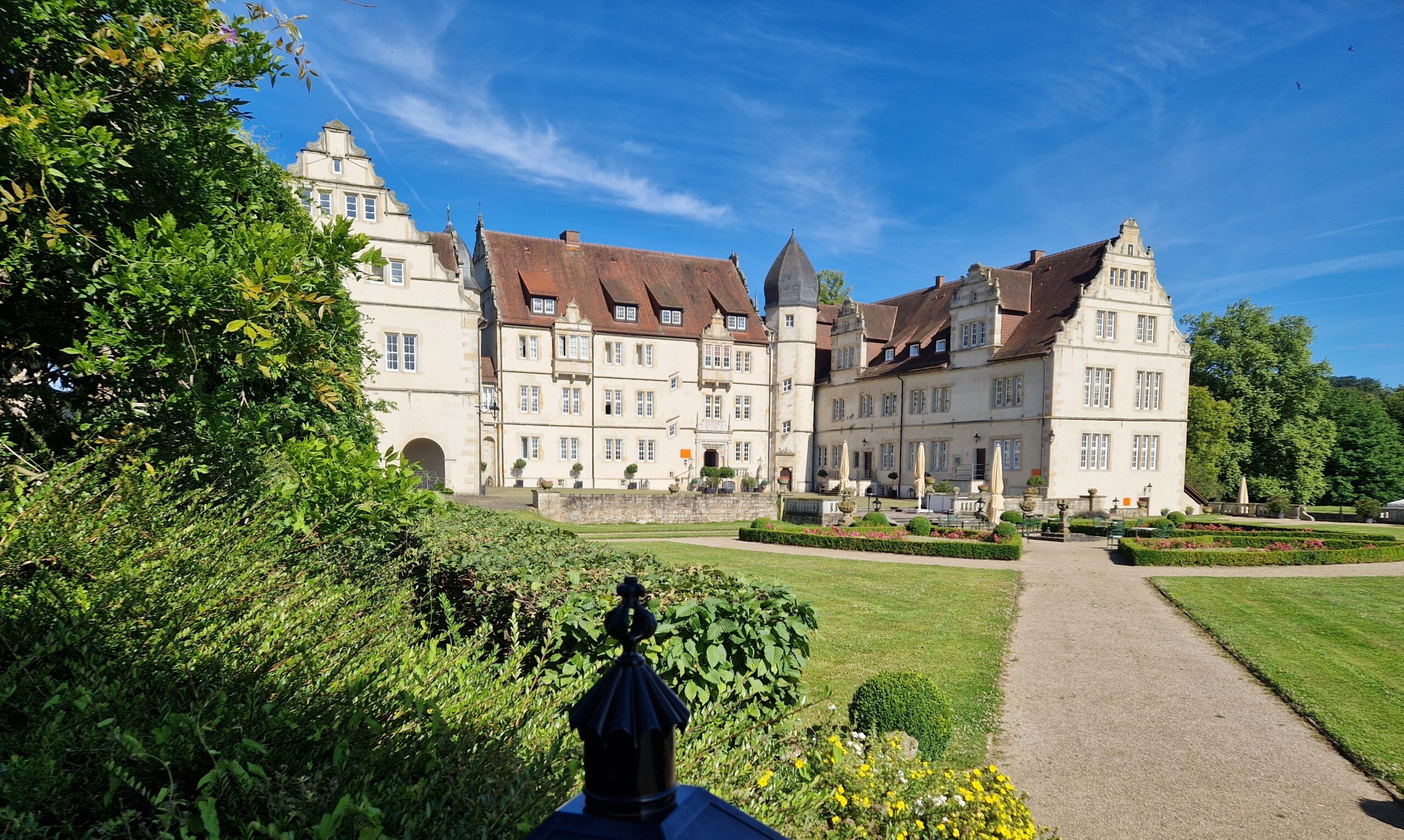 20240709_093122 Blick auf das Schloss, links Sträucher, im Vordergrund eine schwarze Laterne
